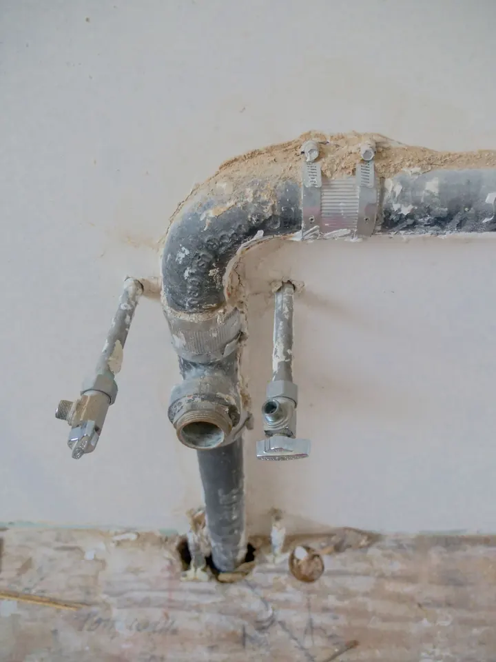 Exposed plumbing pipes inside an opened wall
