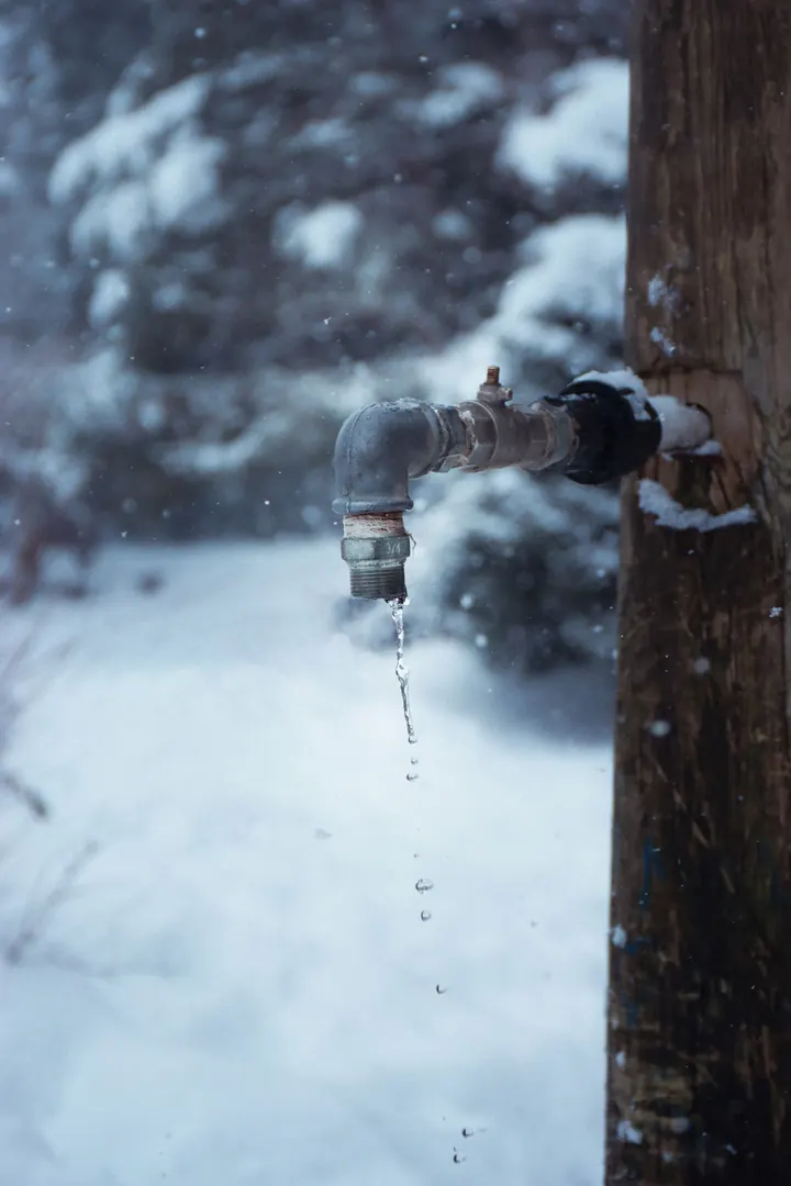 Frozen outdoor water tap dripping in winter